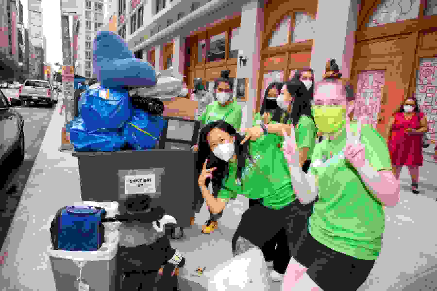 SVA students and family members pose outside wearing masks with a bin filled with dorm room essentials.
