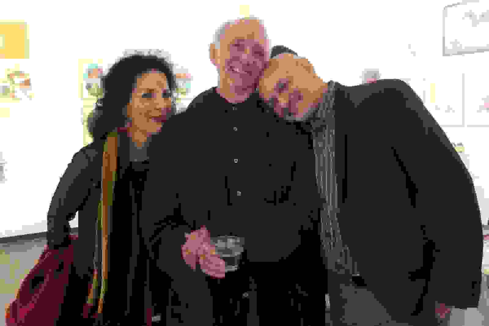 A photograph of three people at an art exhibition.