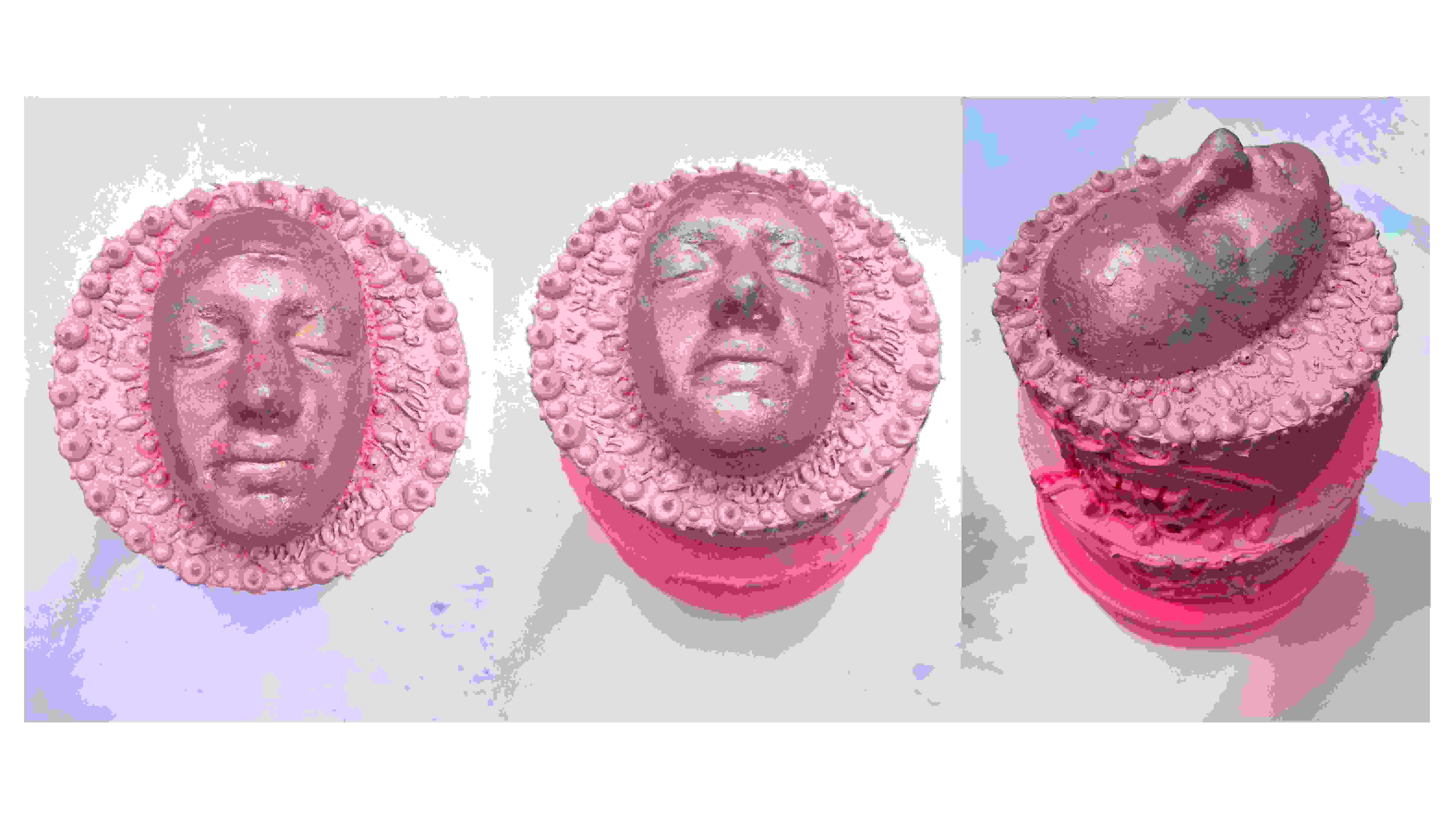 Pink sculpture of a face with decorative elements around the face. 